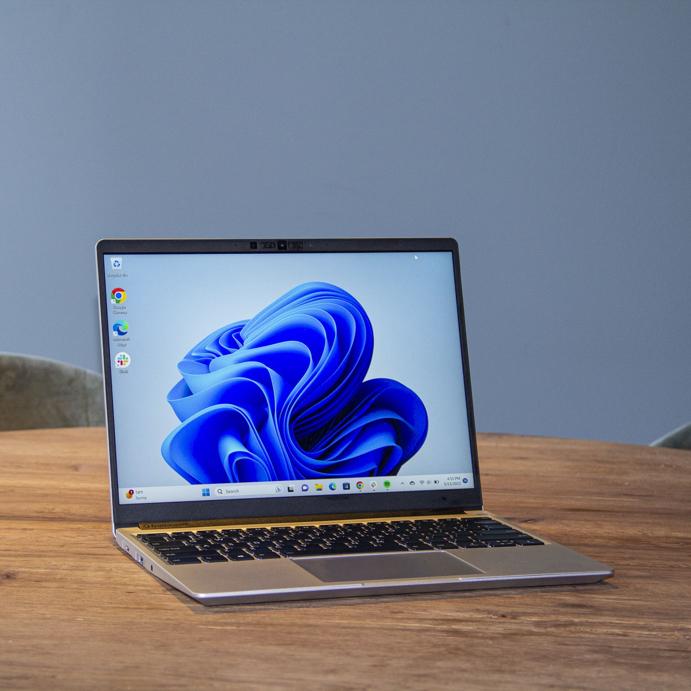 Best Laptop 2023: The Framework Laptop on a wooden table displaying a blue desktop background.