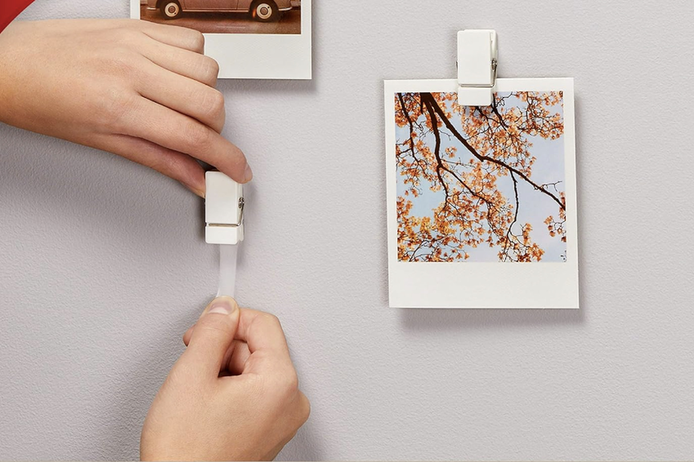 Hand taping clip to the wall, other clips hold photos